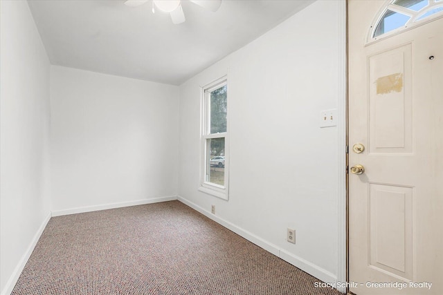 carpeted empty room featuring a ceiling fan, baseboards, and a wealth of natural light