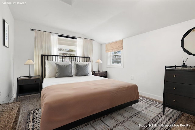 bedroom with lofted ceiling and baseboards