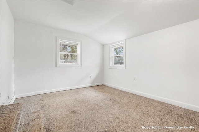 spare room featuring vaulted ceiling, carpet, and baseboards