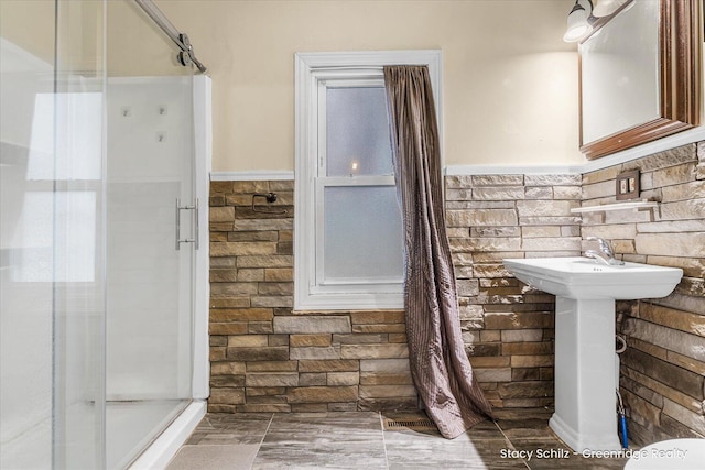 full bathroom featuring a wainscoted wall and a shower stall