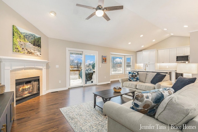 living area featuring a fireplace, dark wood finished floors, lofted ceiling, visible vents, and baseboards