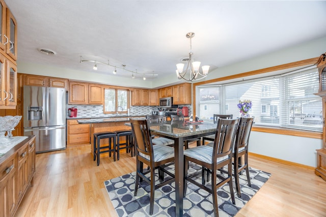 dining area featuring a chandelier, baseboards, visible vents, and light wood finished floors