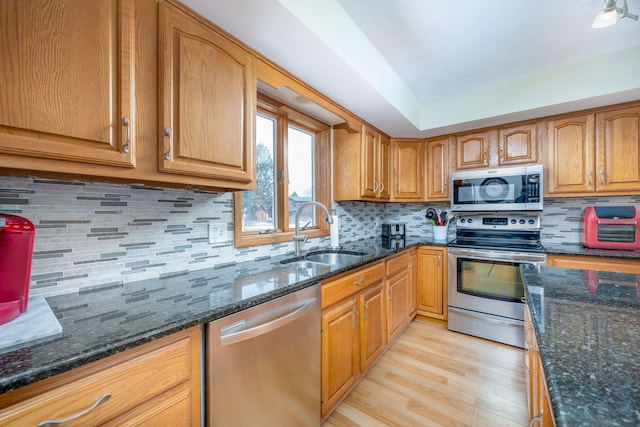 8581 Lynwood Ln, Mecosta, MI 49332 - kitchen featuring a sink, light wood finished floors, dark stone countertops, stainless steel appliances, and tasteful backsplash