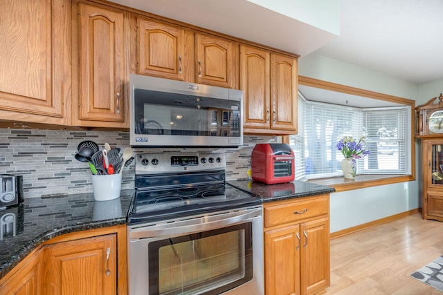 8581 Lynwood Ln, Mecosta, MI 49332 - kitchen with baseboards, dark stone counters, brown cabinets, tasteful backsplash, and stainless steel appliances