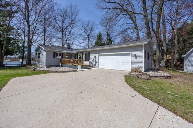 8581 Lynwood Ln, Mecosta, MI 49332 - ranch-style home featuring a front yard, a deck, a chimney, an attached garage, and driveway