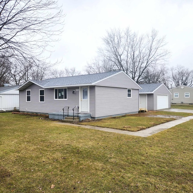 single story home featuring roof with shingles, a front yard, a detached garage, and an outbuilding