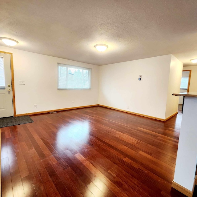 unfurnished room featuring a textured ceiling, wood-type flooring, and baseboards