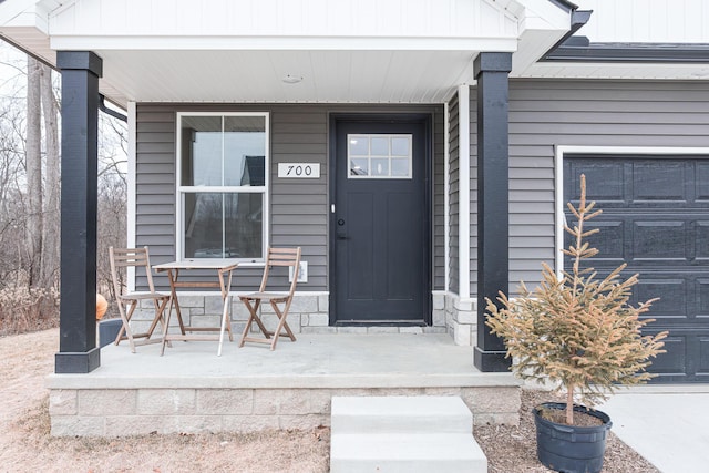 view of exterior entry with a porch and a garage