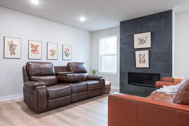 living room with recessed lighting, a tile fireplace, light wood-style flooring, and baseboards