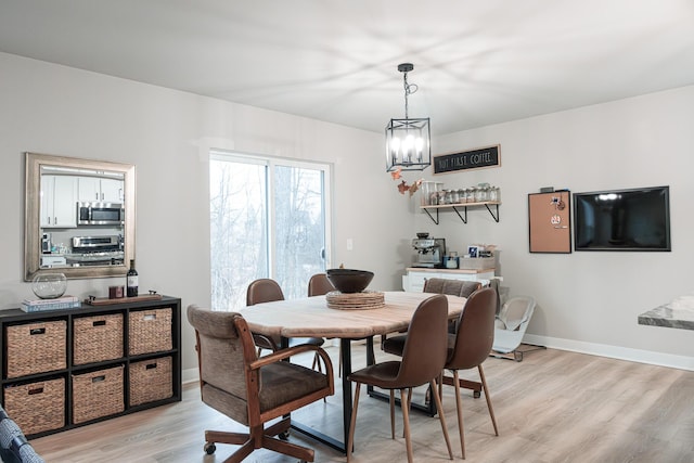 dining space featuring a chandelier, baseboards, and light wood finished floors