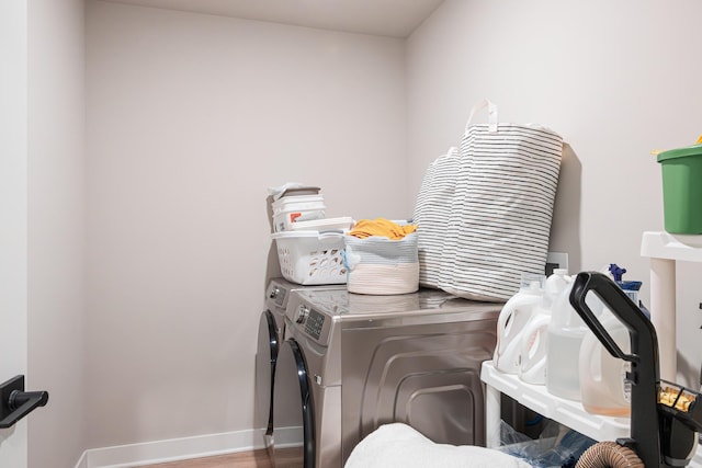 clothes washing area with laundry area, independent washer and dryer, wood finished floors, and baseboards