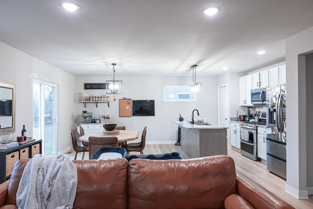 living room featuring baseboards, light wood-type flooring, and recessed lighting