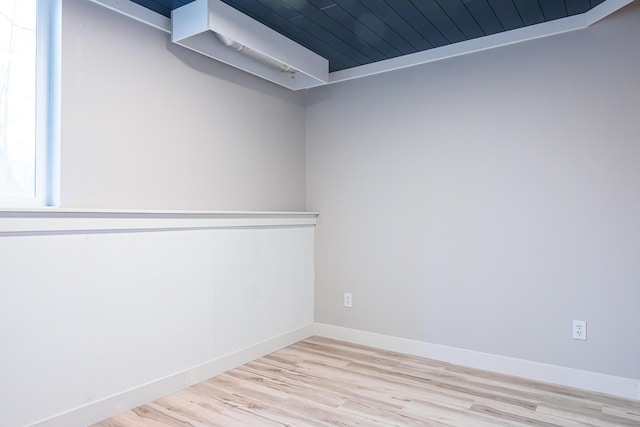 spare room with baseboards and wood finished floors