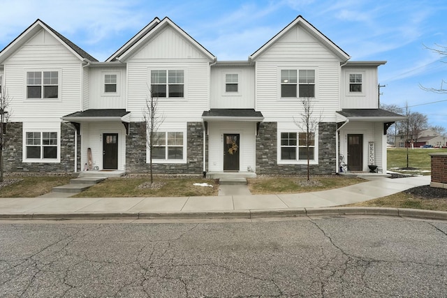 townhome / multi-family property featuring stone siding, board and batten siding, and roof with shingles