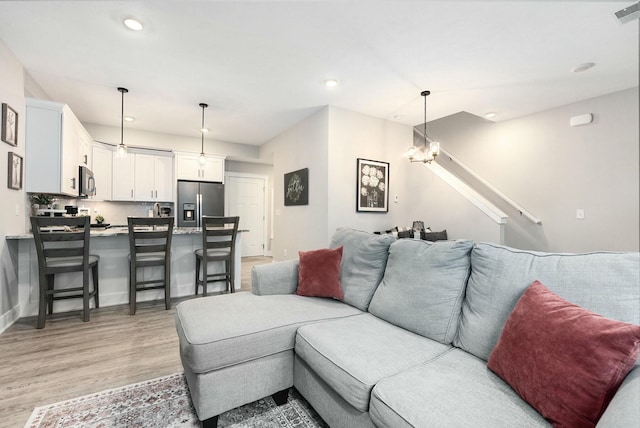 living area with recessed lighting, baseboards, light wood finished floors, and an inviting chandelier