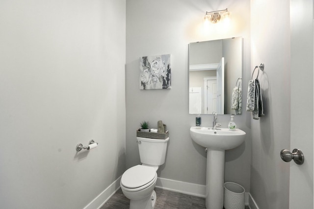 bathroom with toilet, a sink, baseboards, and wood finished floors