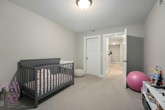 bedroom with carpet floors, visible vents, baseboards, and a textured ceiling