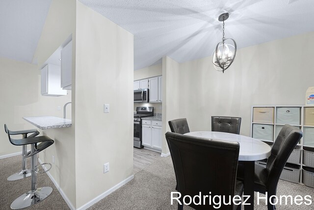 dining room with a chandelier, light colored carpet, and baseboards