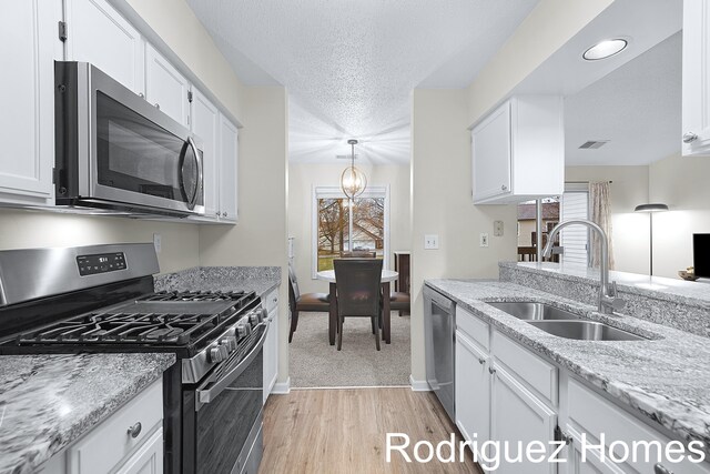 kitchen featuring visible vents, appliances with stainless steel finishes, white cabinets, a sink, and a textured ceiling