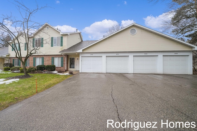 traditional home with brick siding, a front yard, and community garages