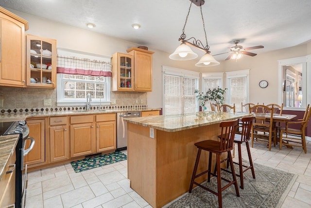 kitchen featuring light stone counters, a breakfast bar, a kitchen island, a sink, and appliances with stainless steel finishes