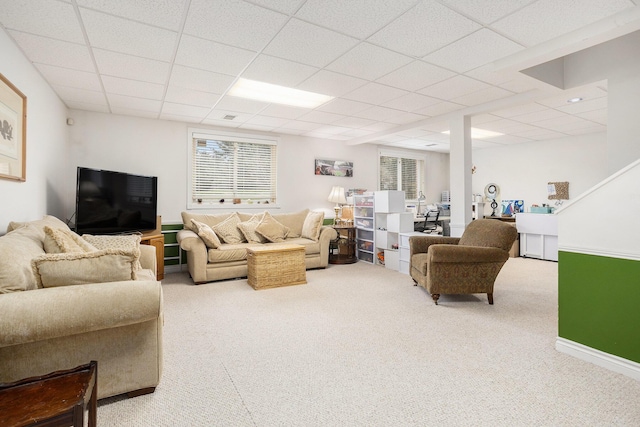 carpeted living room featuring a paneled ceiling and baseboards