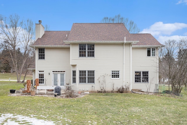 rear view of property with a yard, roof with shingles, a chimney, and french doors