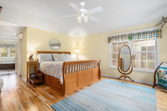 bedroom with light wood finished floors, ceiling fan, baseboards, and a textured ceiling