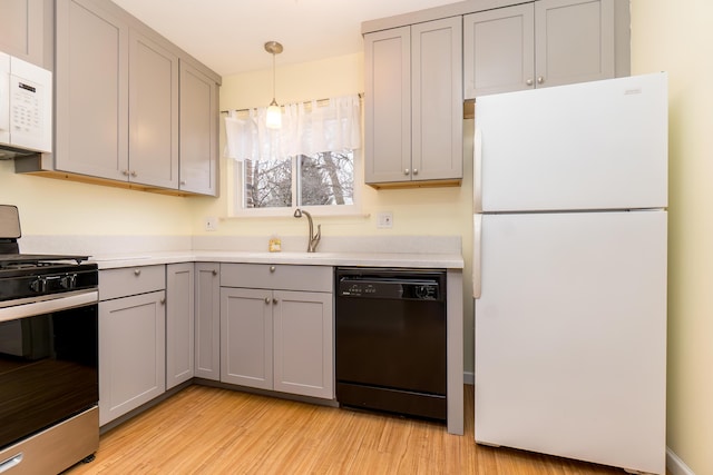 kitchen with white appliances, light countertops, gray cabinetry, light wood-type flooring, and a sink