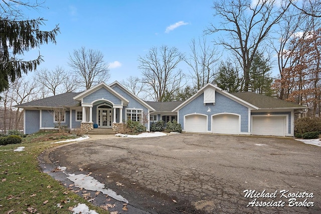 view of front facade with a garage, french doors, and aphalt driveway