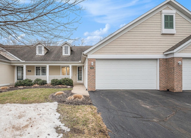 view of front facade with driveway, an attached garage, a porch, and brick siding