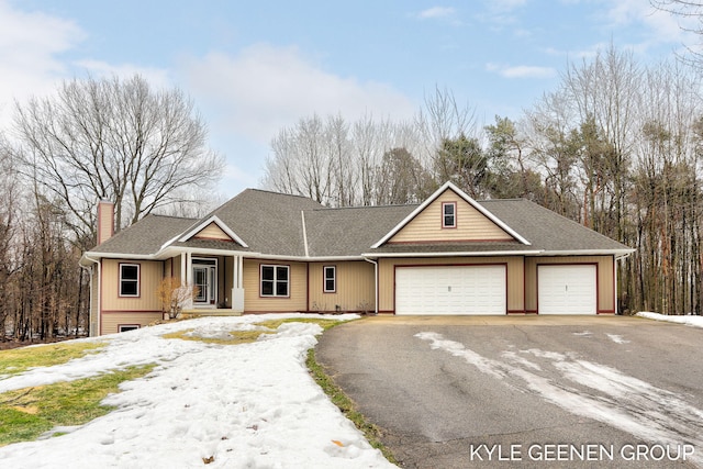 view of front of home with driveway, an attached garage, a chimney, and roof with shingles