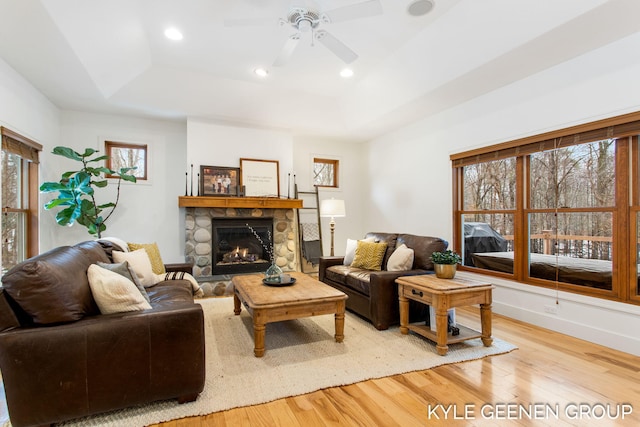 living area with a tray ceiling, a fireplace, recessed lighting, wood finished floors, and baseboards