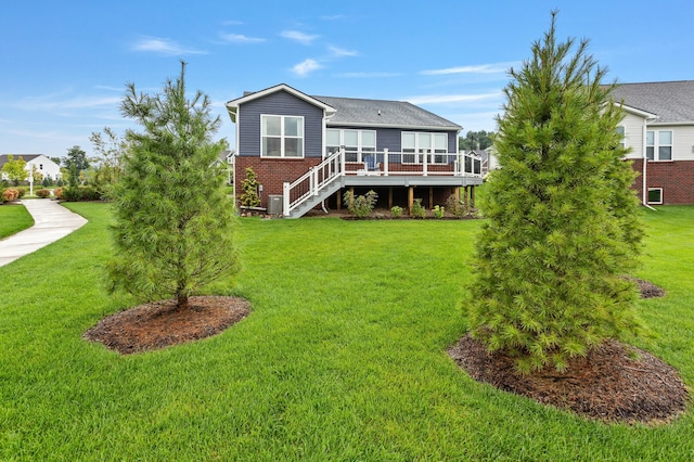 view of front of house featuring a front yard, brick siding, a deck, and stairs