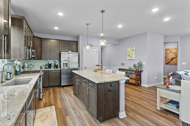 kitchen featuring stainless steel appliances, wood finished floors, a sink, and dark brown cabinetry