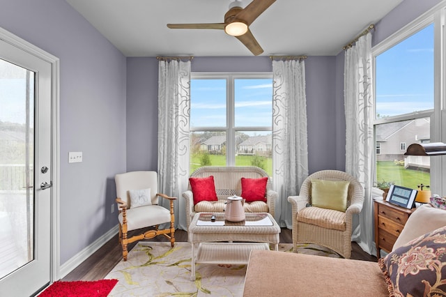 living area with wood finished floors, a ceiling fan, and baseboards