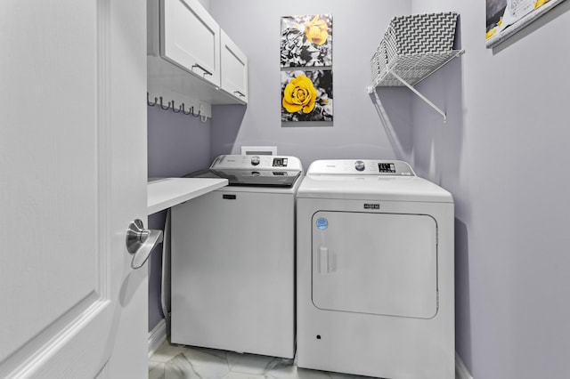 clothes washing area featuring washer and dryer, marble finish floor, and cabinet space