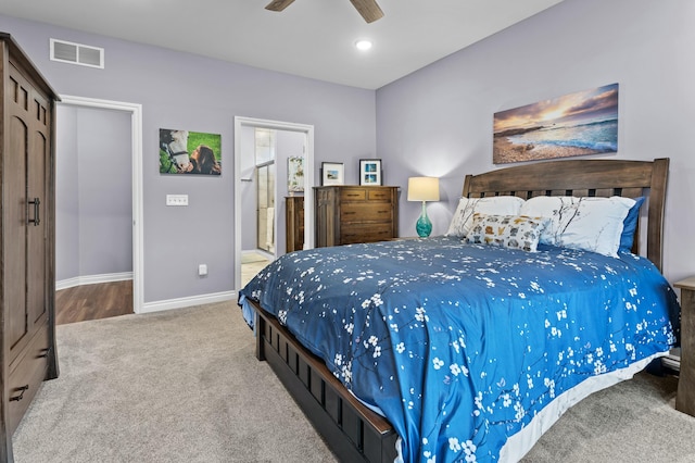 carpeted bedroom with a ceiling fan, visible vents, baseboards, and ensuite bathroom