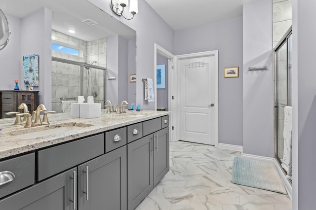 bathroom featuring a stall shower, marble finish floor, a sink, and double vanity