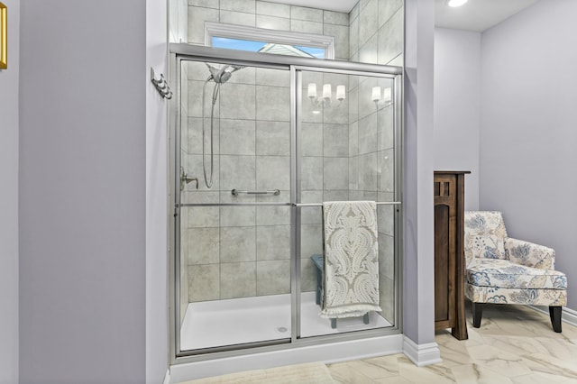 bathroom featuring marble finish floor, a shower stall, and baseboards