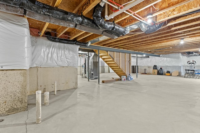 unfinished basement featuring stairs and heating unit