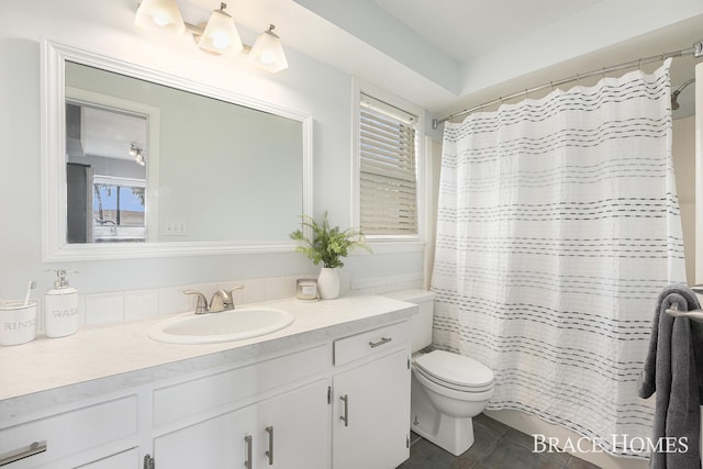 bathroom with a shower with curtain, vanity, toilet, and tile patterned floors