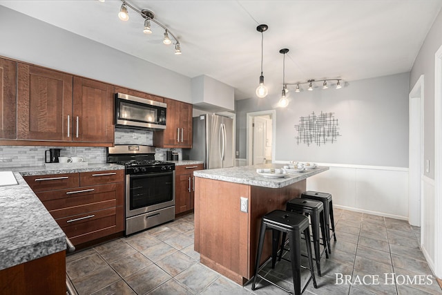 kitchen featuring a breakfast bar area, light countertops, decorative backsplash, appliances with stainless steel finishes, and a kitchen island