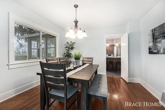 dining space with an inviting chandelier, baseboards, and wood finished floors