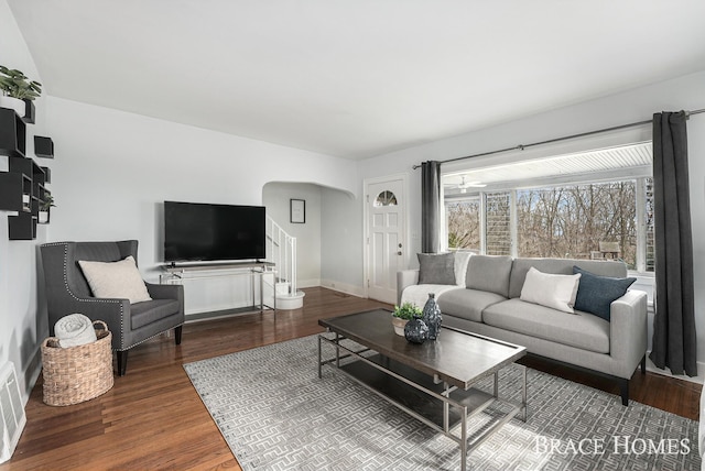 living area featuring arched walkways, wood finished floors, and baseboards