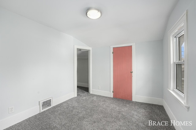 unfurnished bedroom featuring carpet floors, lofted ceiling, visible vents, and baseboards