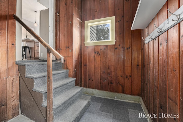 stairs featuring carpet and wood walls