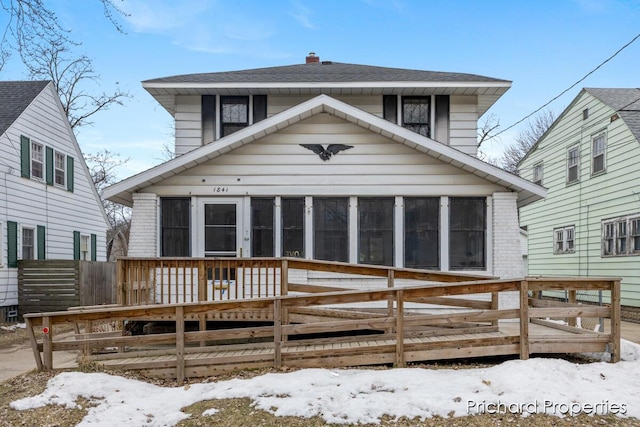 view of front of home with a sunroom, a deck, and brick siding