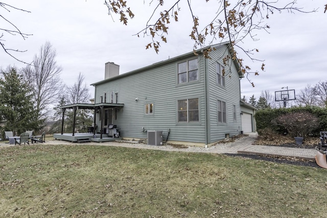 back of house featuring central AC, a yard, a chimney, and an attached garage