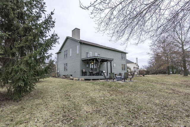 rear view of house with a chimney and a lawn